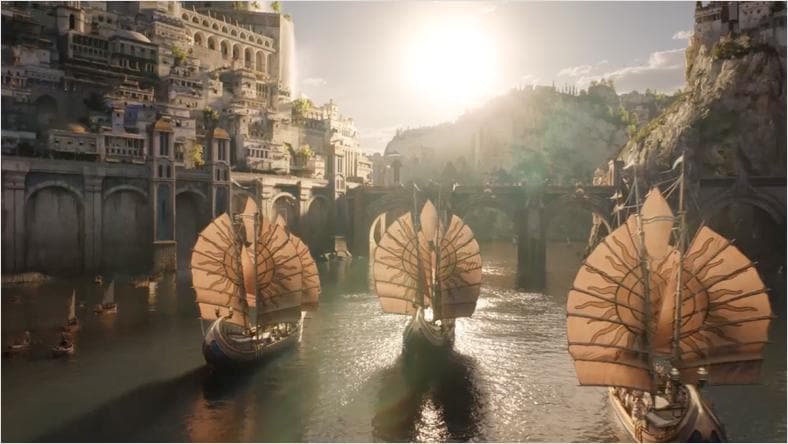 Three large sailing ships with prominent, fan-shaped sails navigate a river surrounded by a city built into rocky cliffs, under a bright sun.