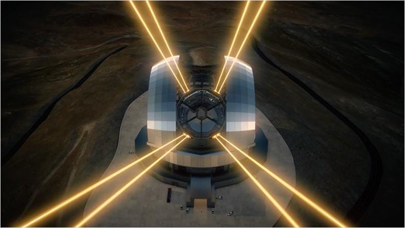 A large telescope illuminated by bright lights, set against a dark background.