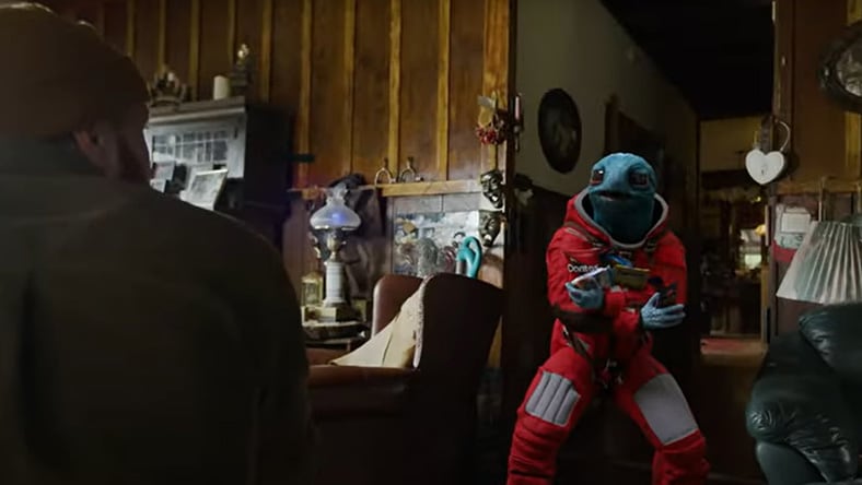 Blue alien in red spacesuit with Doritos in a cozy room
