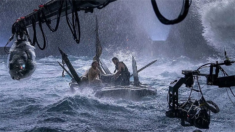 Two actors being filmed on the water during a storm