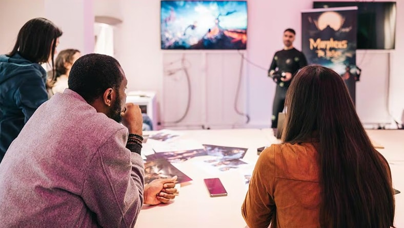 Group of people engaged in a discussion or presentation in a creative or gaming environment.