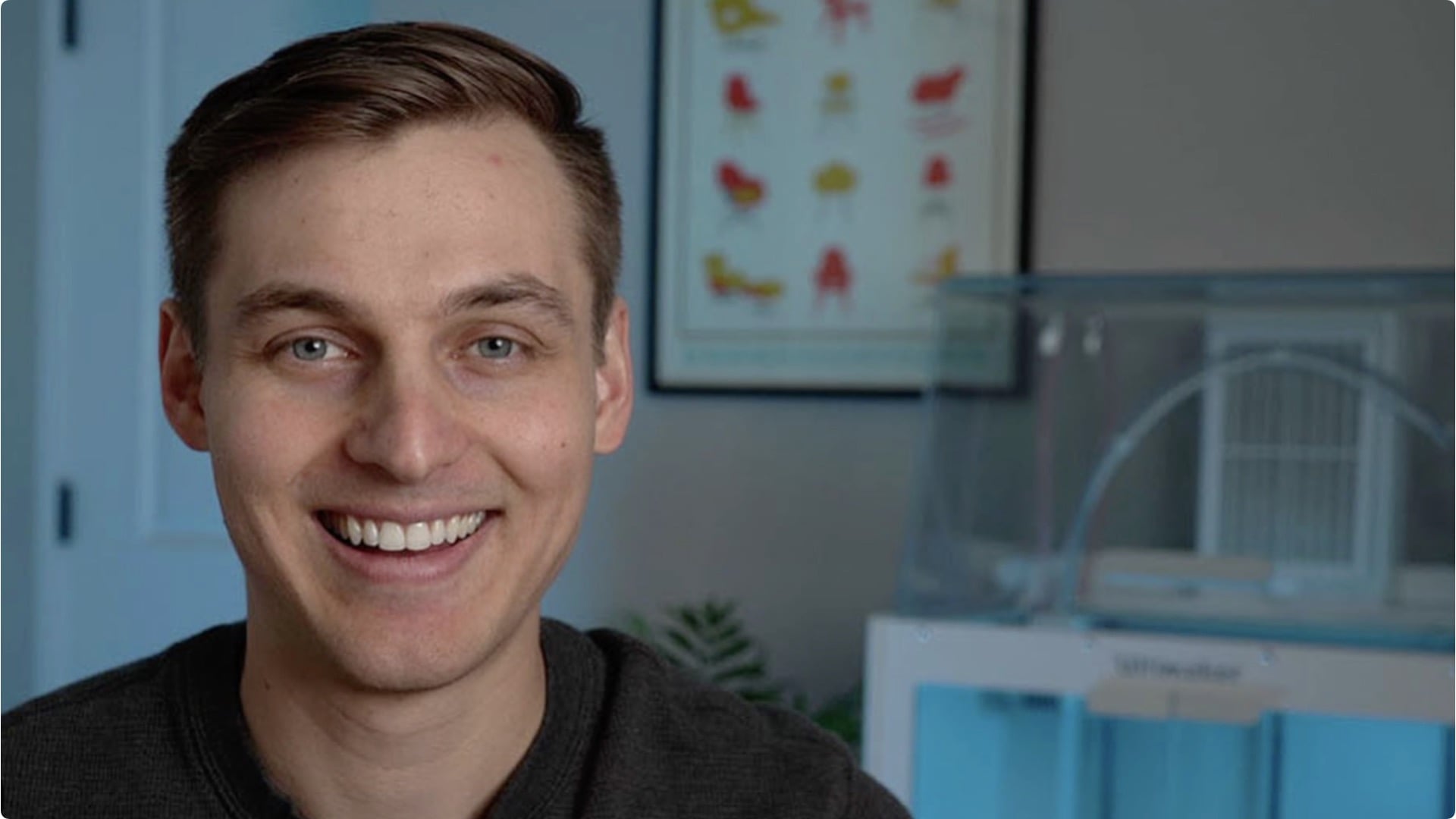 Kevin Kennedy smiling into a web camera with some of his 3D product designs in the background