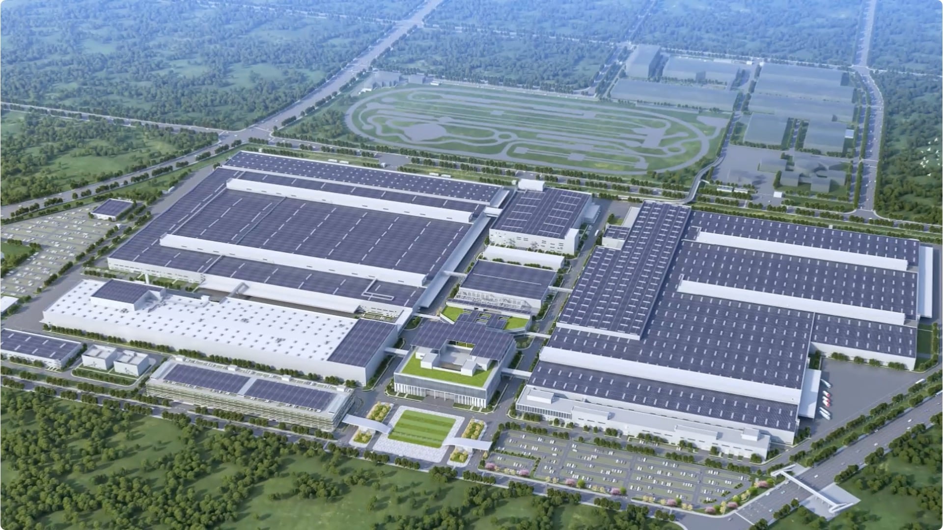 Aerial view of a very large modern manufacturing plant with solar panel arrays covering most of the roof space and surrounded by countryside