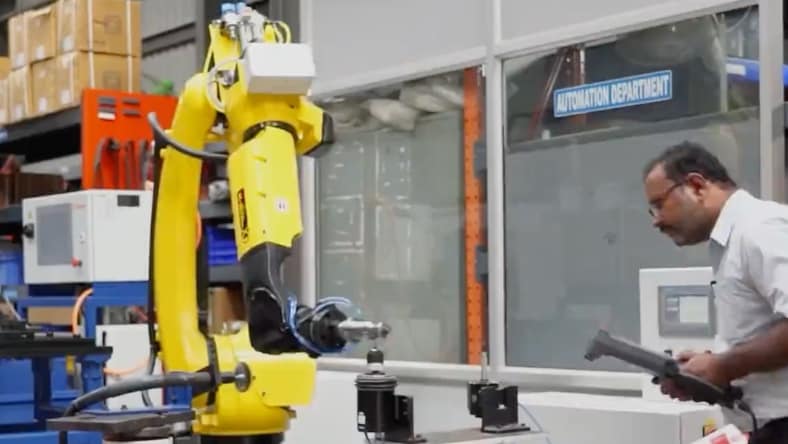 Technician operating and observing a robotic assembly device