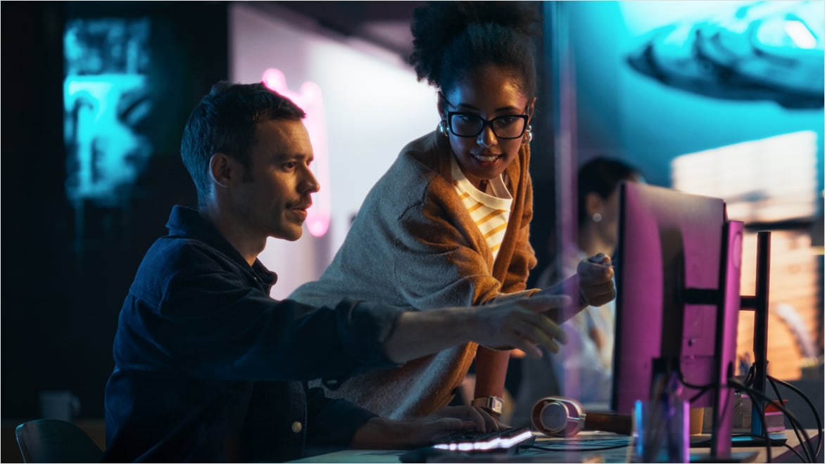 Man and woman reviewing content on monitor
