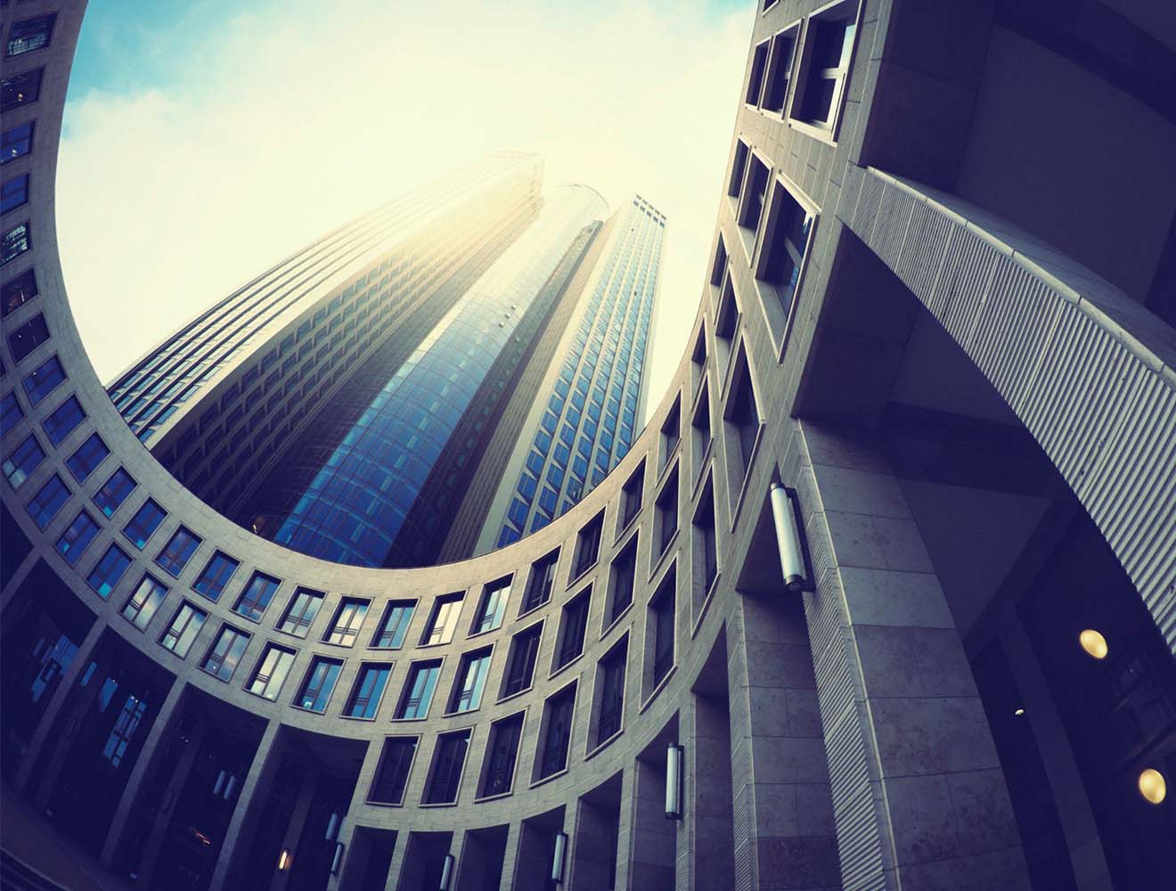 Modern high‑rise buildings viewed from a circular architectural courtyard.