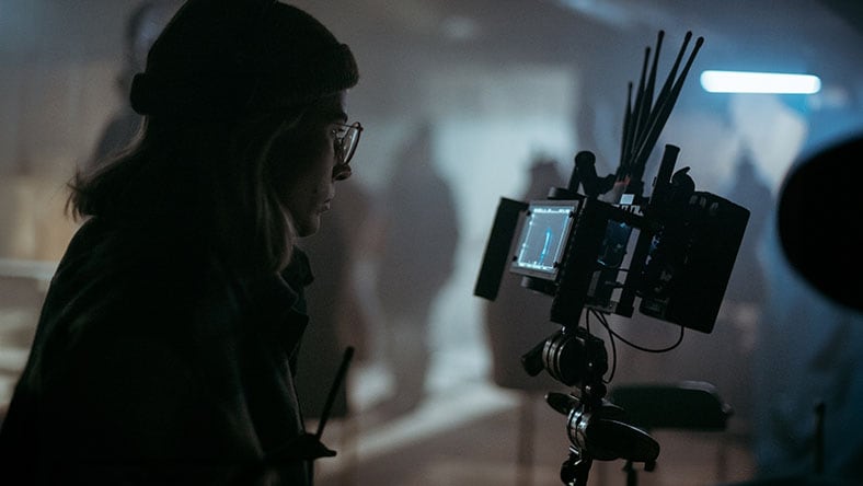 A filmmaker on set looking at a monitor.