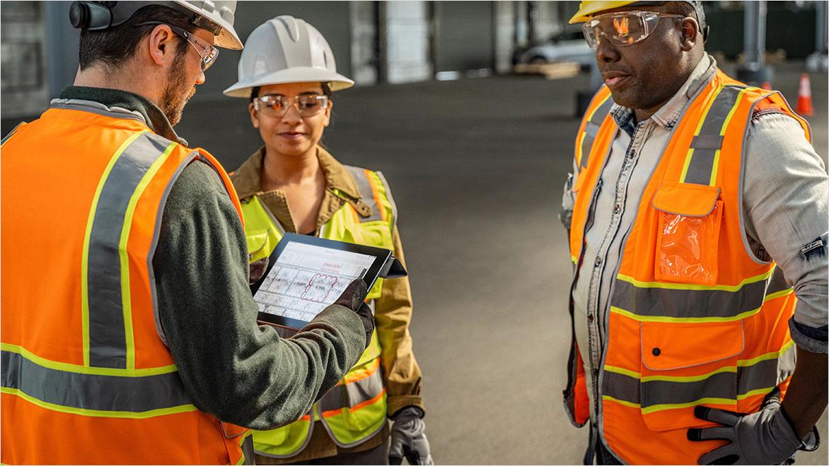 Workers viewing a digital tablet at a construction site.
