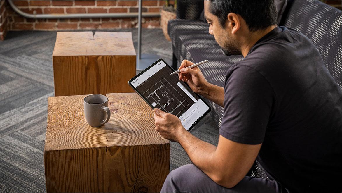 Student using tablet and stylus to learn architectural drafting with a digital floor plan.