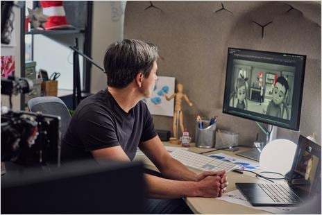 Aidan Sugano, The Cat in the Hat production designer, seated at a desk reviewing digital artwork on a computer monitor. 