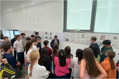 A group of students gather around design boards