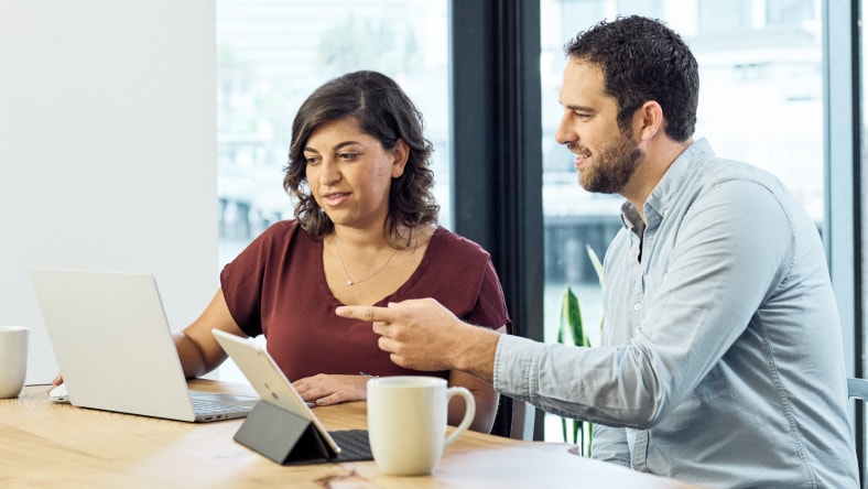 Two employees in conversation across a desk, representing HR or people partner collaboration