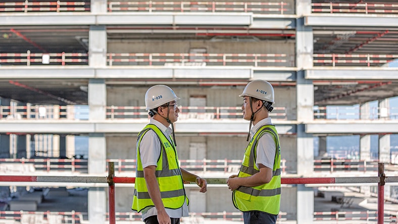 Construction workers discussing project progress at high-rise building site.