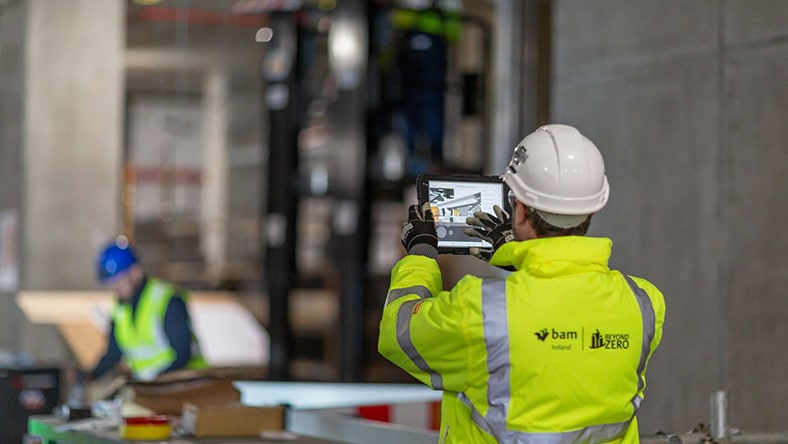 Construction worker reviewing digital building plans on tablet indoors.