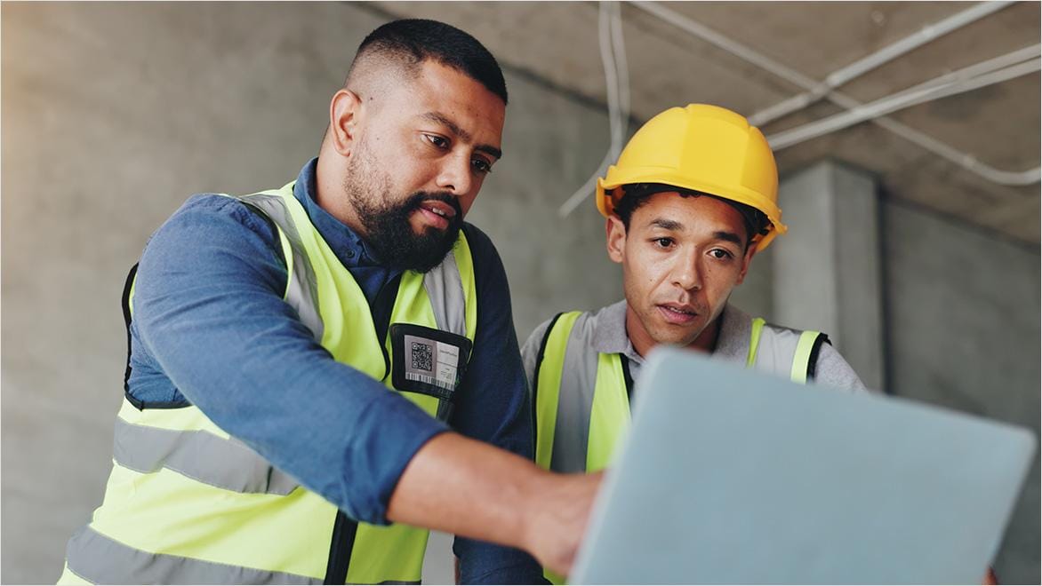Engineers reviewing digital construction models with AI software in an industrial warehouse.