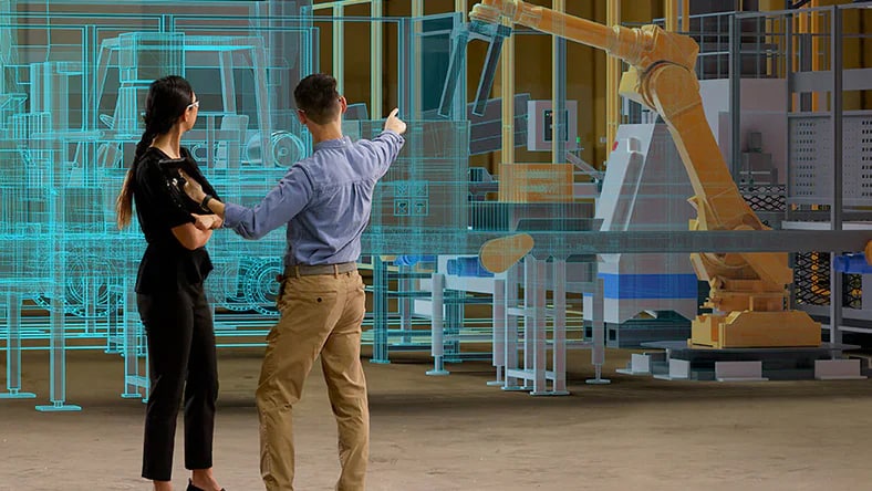 A woman and a man stand in front of a digital representation of a factory machine. He points at it.