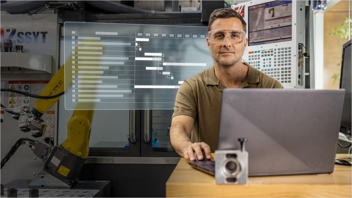 Engineer using Autodesk Fusion for Design for planning beside robotic automation equipment.