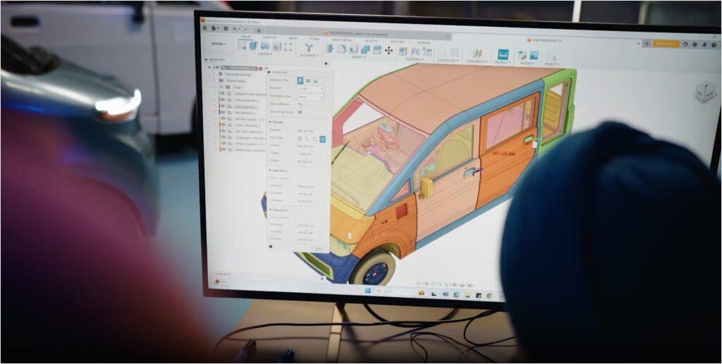 Designer reviewing a colorful camper van concept model in Autodesk Fusion on a desktop monitor.