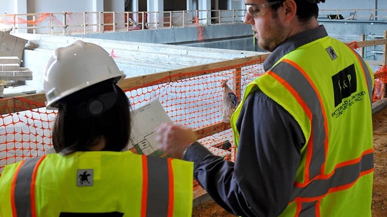Two construction workers consult project notes on a jobsite.