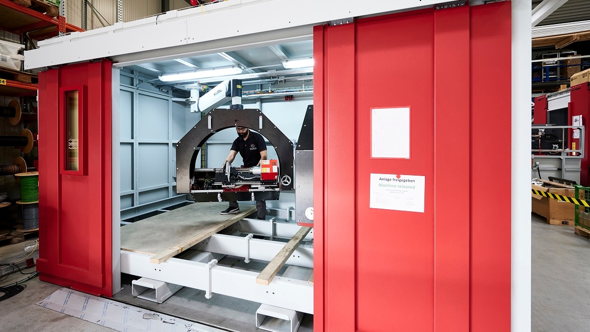 Un employé ajuste l'équipement radioscopique à l'intérieur d'une grande cabine de protection à rayons X