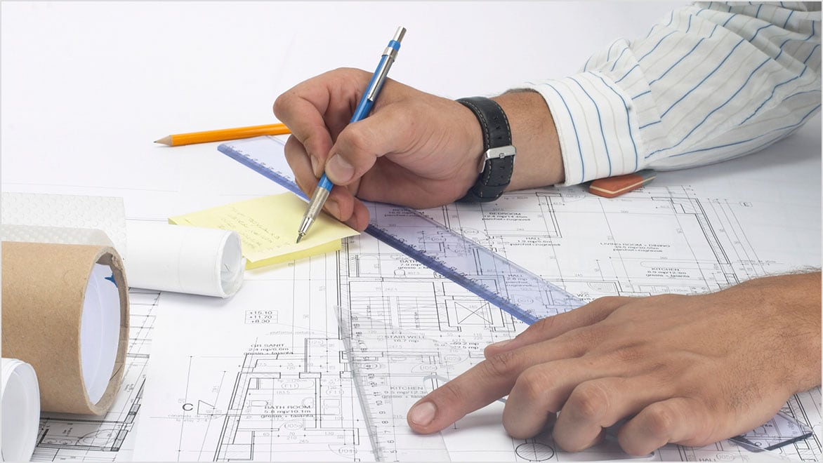 Close-up view of an architect working on blueprints.