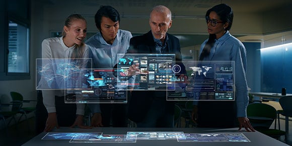 Quatre concepteurs dans un bureau regardant un écran futuriste affichant des hologrammes de réalité augmentée 
