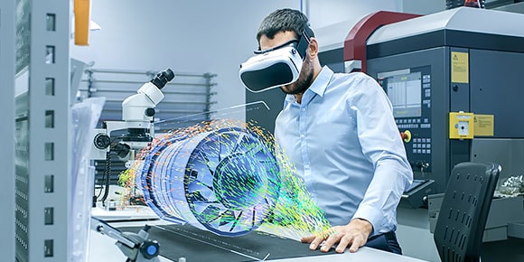 工場で VR ヘッドセットを装着したエンジニアが、ホログラフィック投影テーブル上でエンジン タービンを設計している 