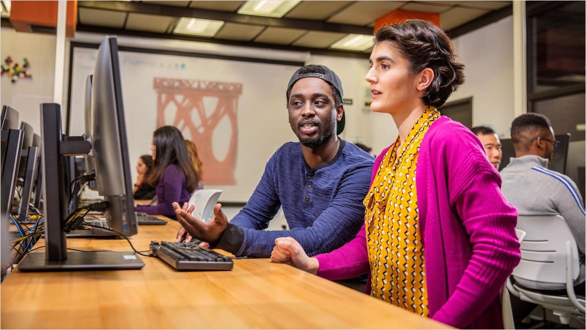 Teachers and students work with design software on computers together in a classroom.