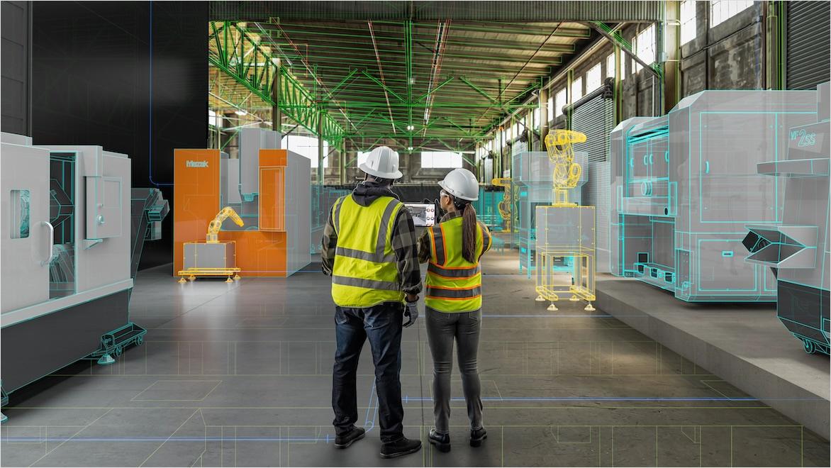 Two workers in safety equipment stand in a partially complete building on a construction site viewing design information on a tablet.