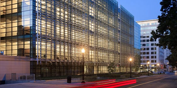 Nighttime view of the Consolidated Forensic Laboratory, a multilevel building featuring floor-to-ceiling glass paneling