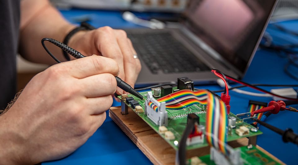 Una persona que utiliza el software de diseño de circuitos impresos mientras trabaja en un dispositivo electrónico