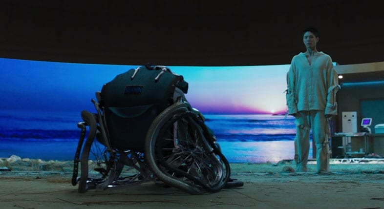 A man gazes at a damaged wheelchair