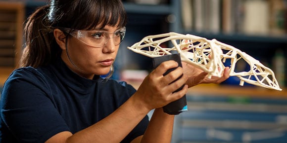 A woman wearing protective goggles while handling a manufactured model 