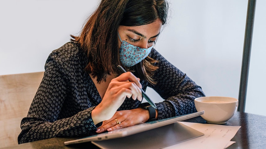 一位戴着口罩使用平板电脑工作的女士