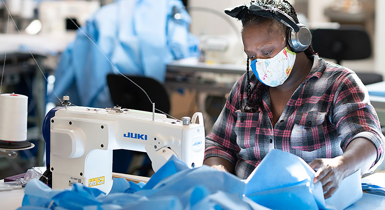 Worker sews personal protective equipment in ISAIC's apparel manufacturing facility