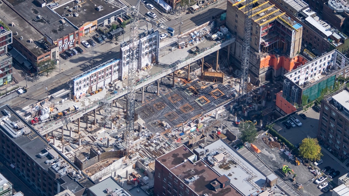 Luftaufnahme der Baustelle KING Toronto mit laufenden unterirdischen Bauarbeiten und den Fassaden denkmalgeschützter Gebäude auf Straßenniveau