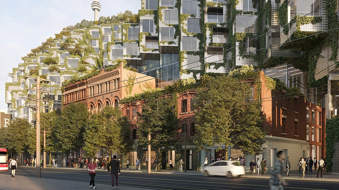 Ein Rendering von KING Toronto zeigt eine Straßenansicht mit historischen Backsteingebäuden, hinter denen modulare Neubaueinheiten wie Berge aufragen