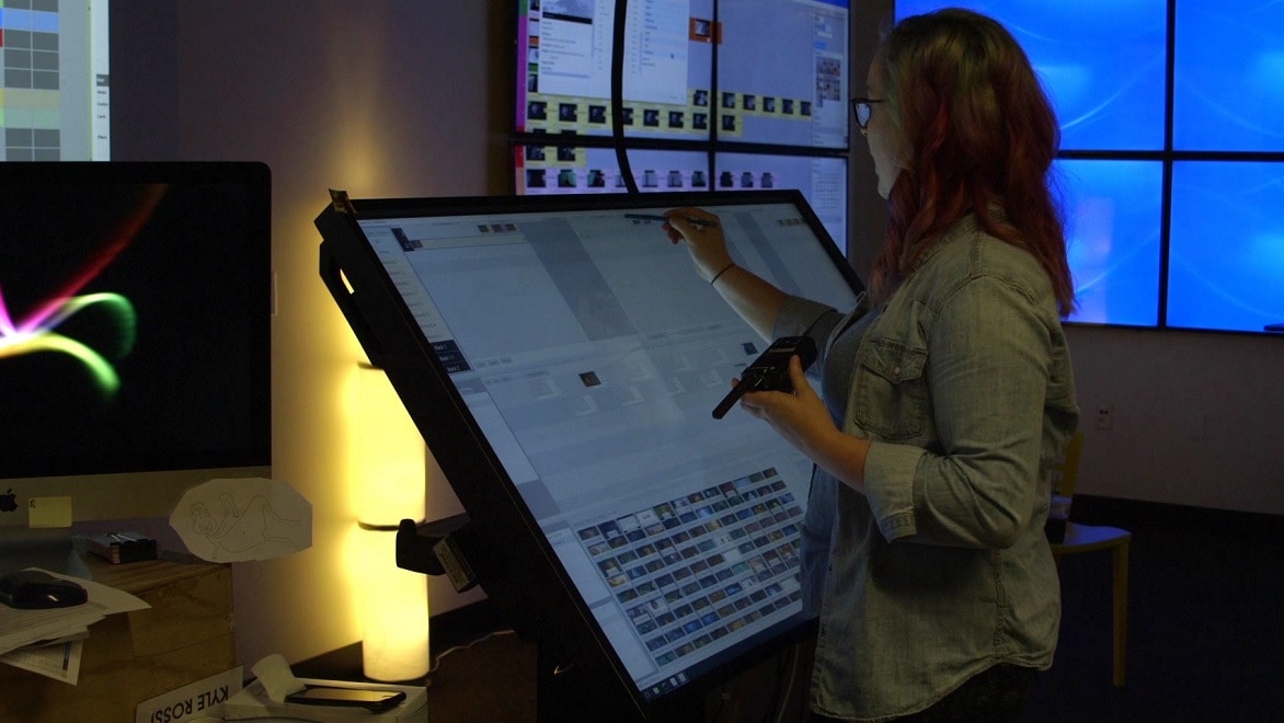 A producer works on a schedule in ShotGrid using a stylus and large computer touchscreen