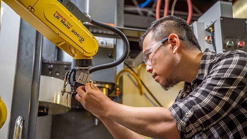 Man works with industrial robot arm.