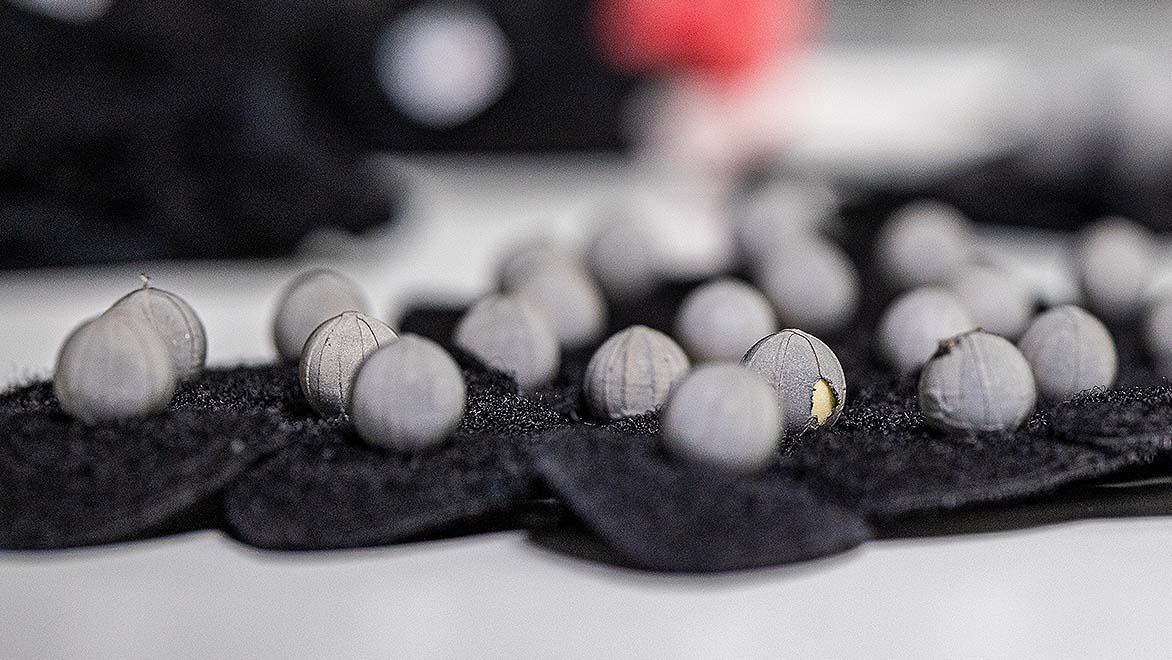 Multiple black, felt circles covered in grey fabric balls