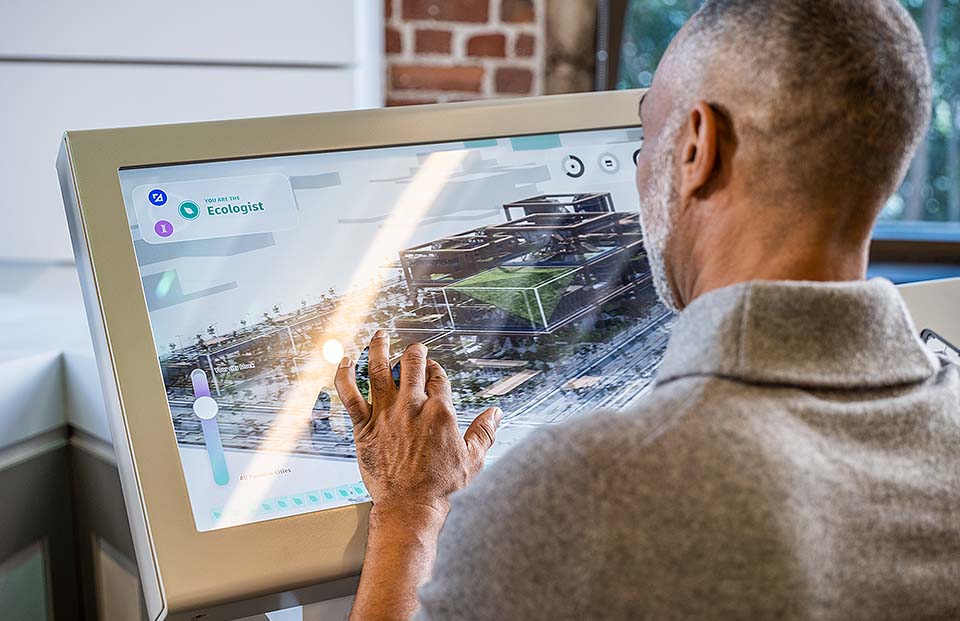 A man using a touchscreen device to design a building.