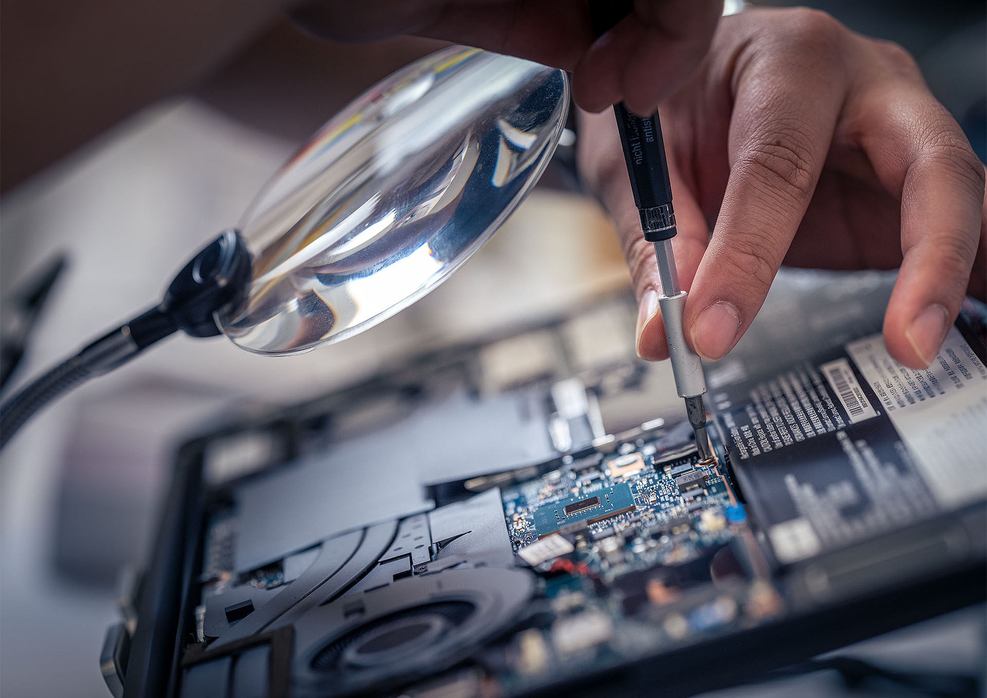 A person screwing in a circuit board to a device. 