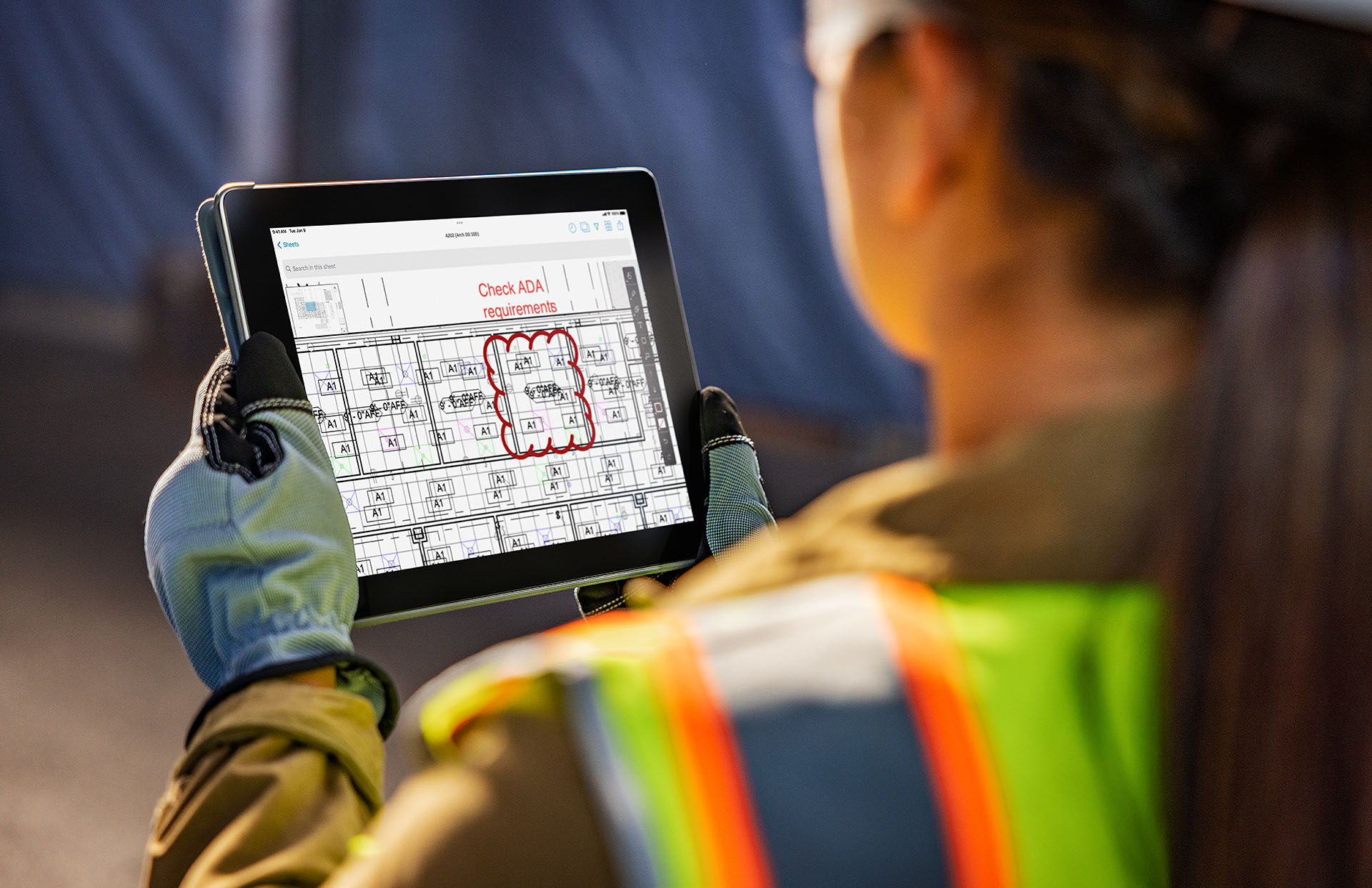 A person looking at a tablet that has a mockup of a building. Red text in the image says, “check ADA requirements.”