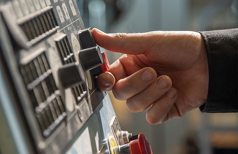 A person turning a knob on a panel.