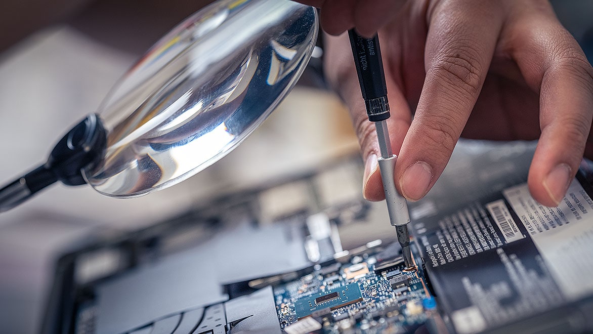 A person screwing in a circuit board to a device.