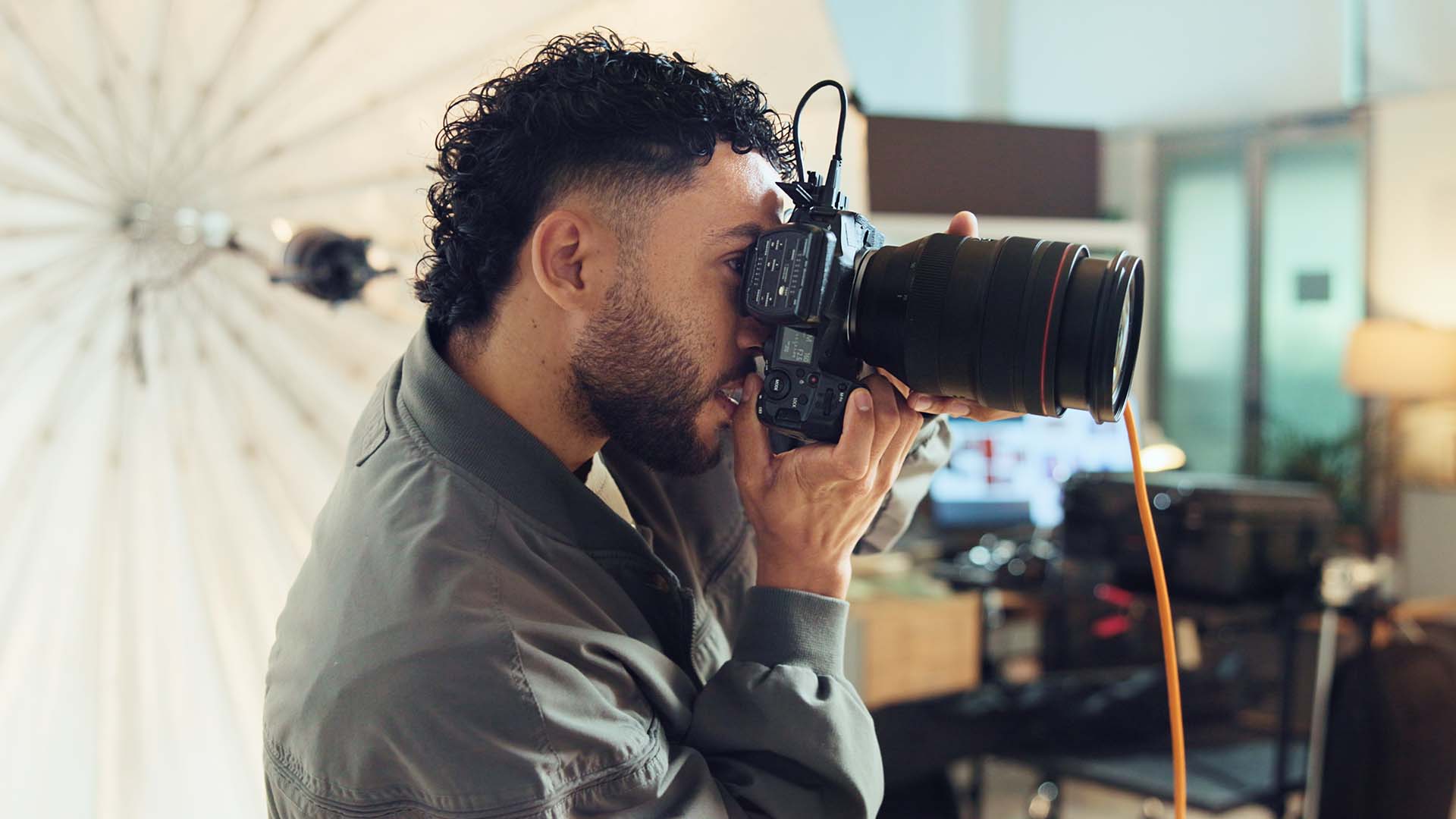 Bearded man looks through camera in a studio