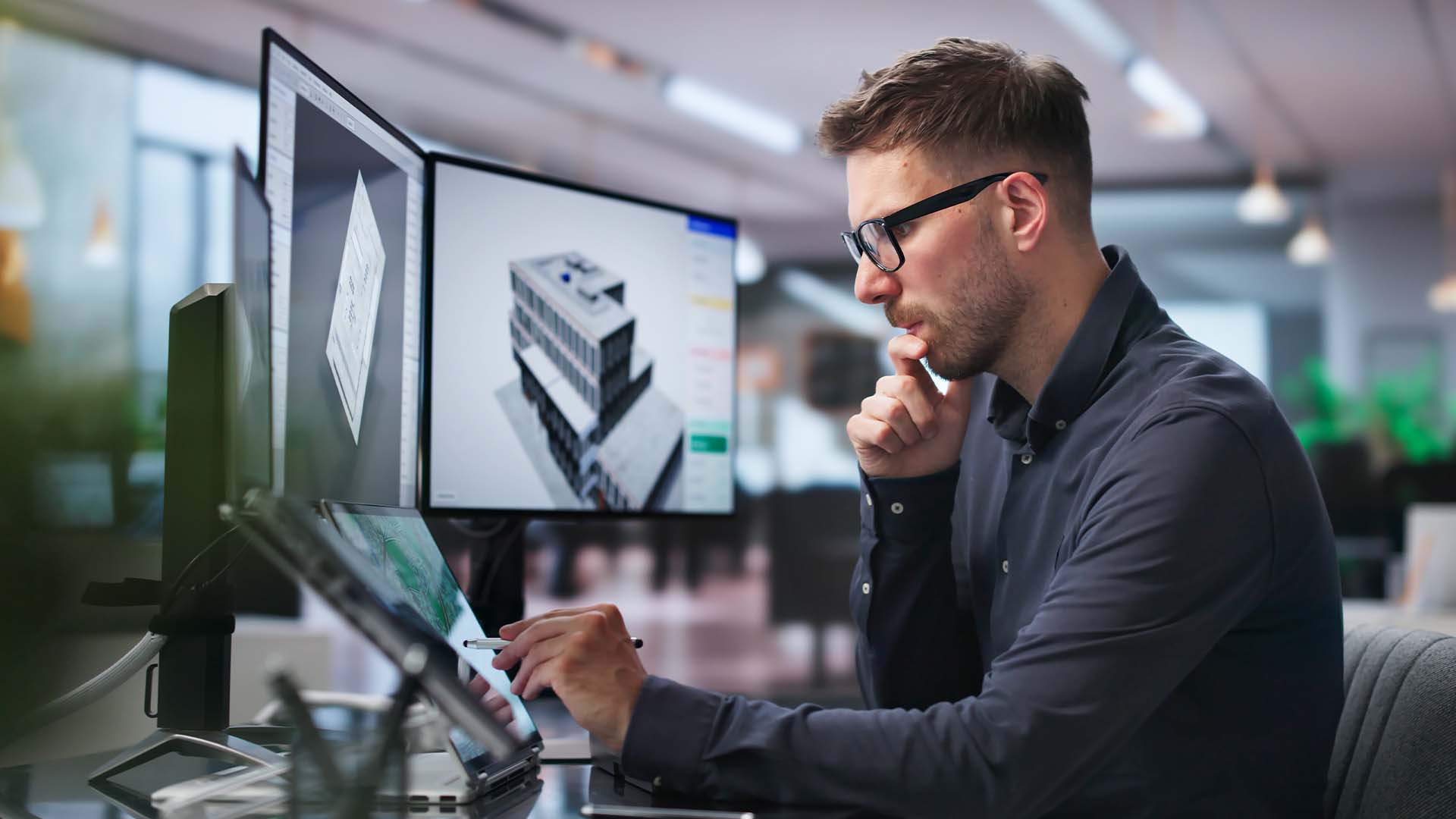 Man at computer works in front of multiple monitors. 