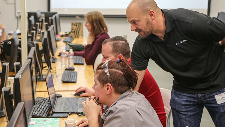 An Autodesk instructor working with adult students in a computer lab