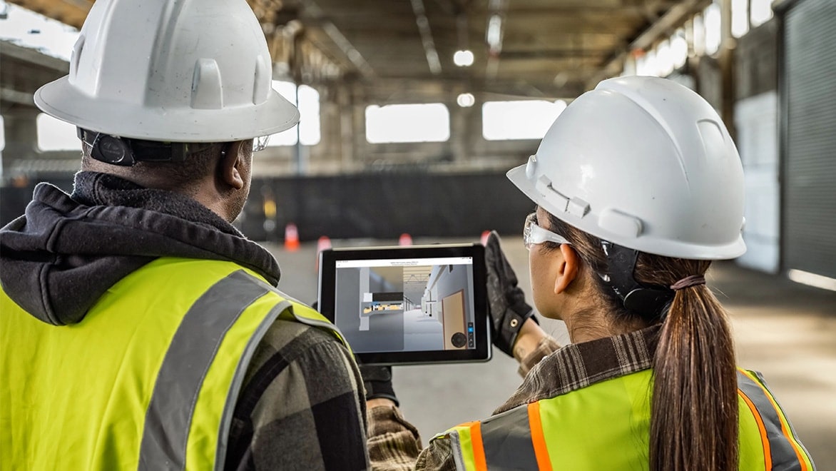 Two construction workers viewing a digital tablet at a construction site