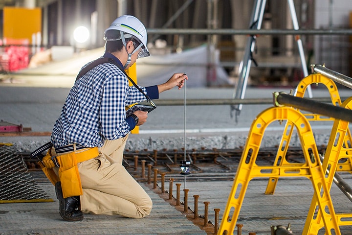 Ein Bauarbeiter nimmt auf einer Baustelle digitale Messungen vor